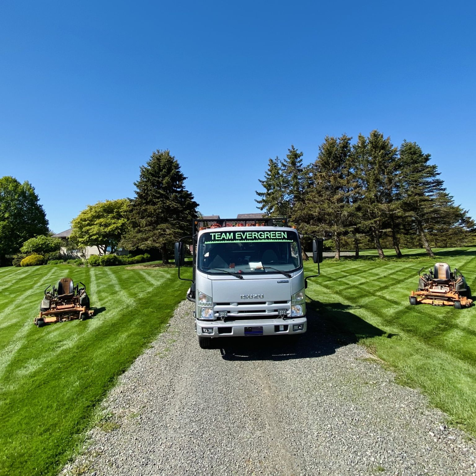 Lawn care Watertown CT with Team Evergreen truck between two mowers on a striped lawn