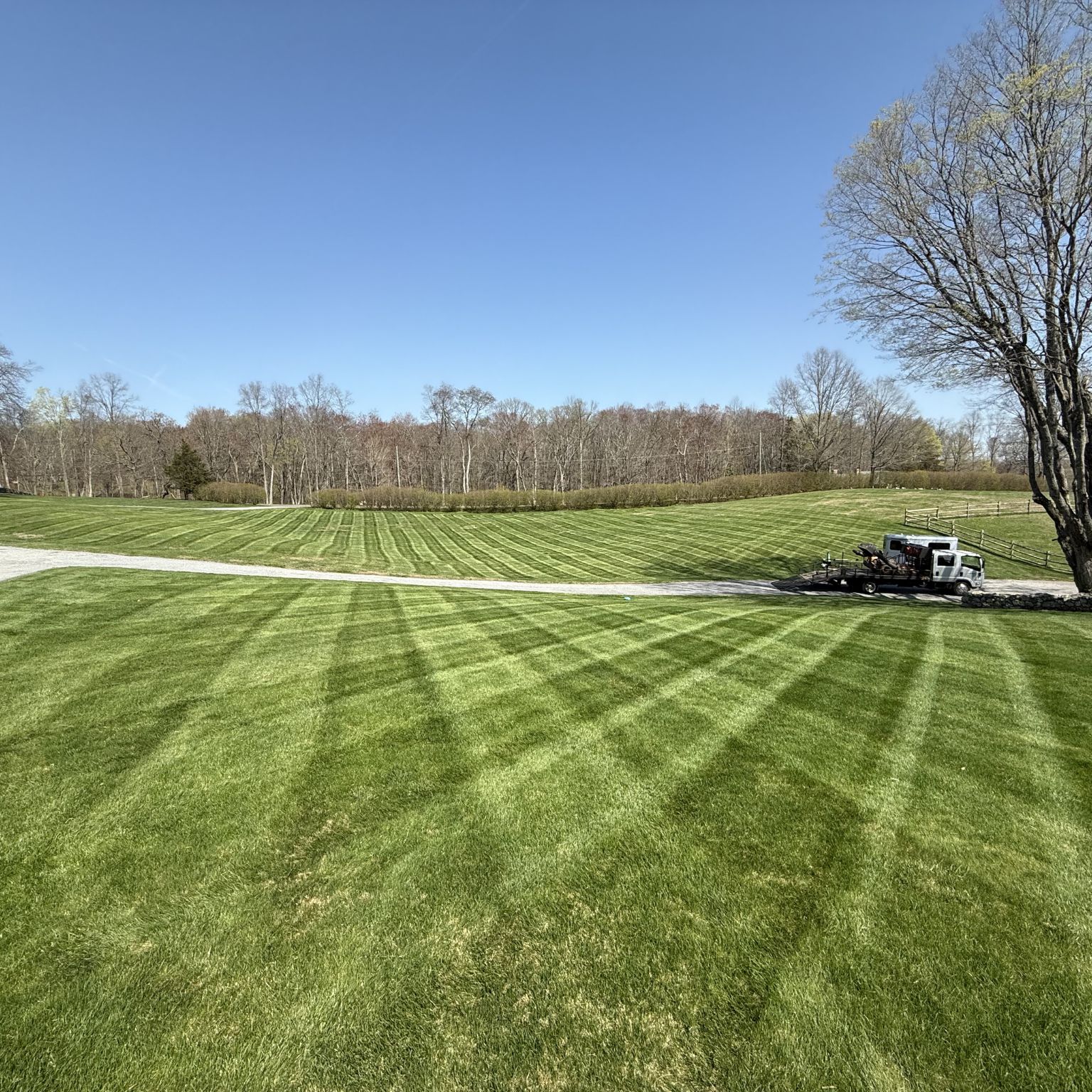 Watertown lawn and garden with a curved driveway, striped turf, and service truck on a large property