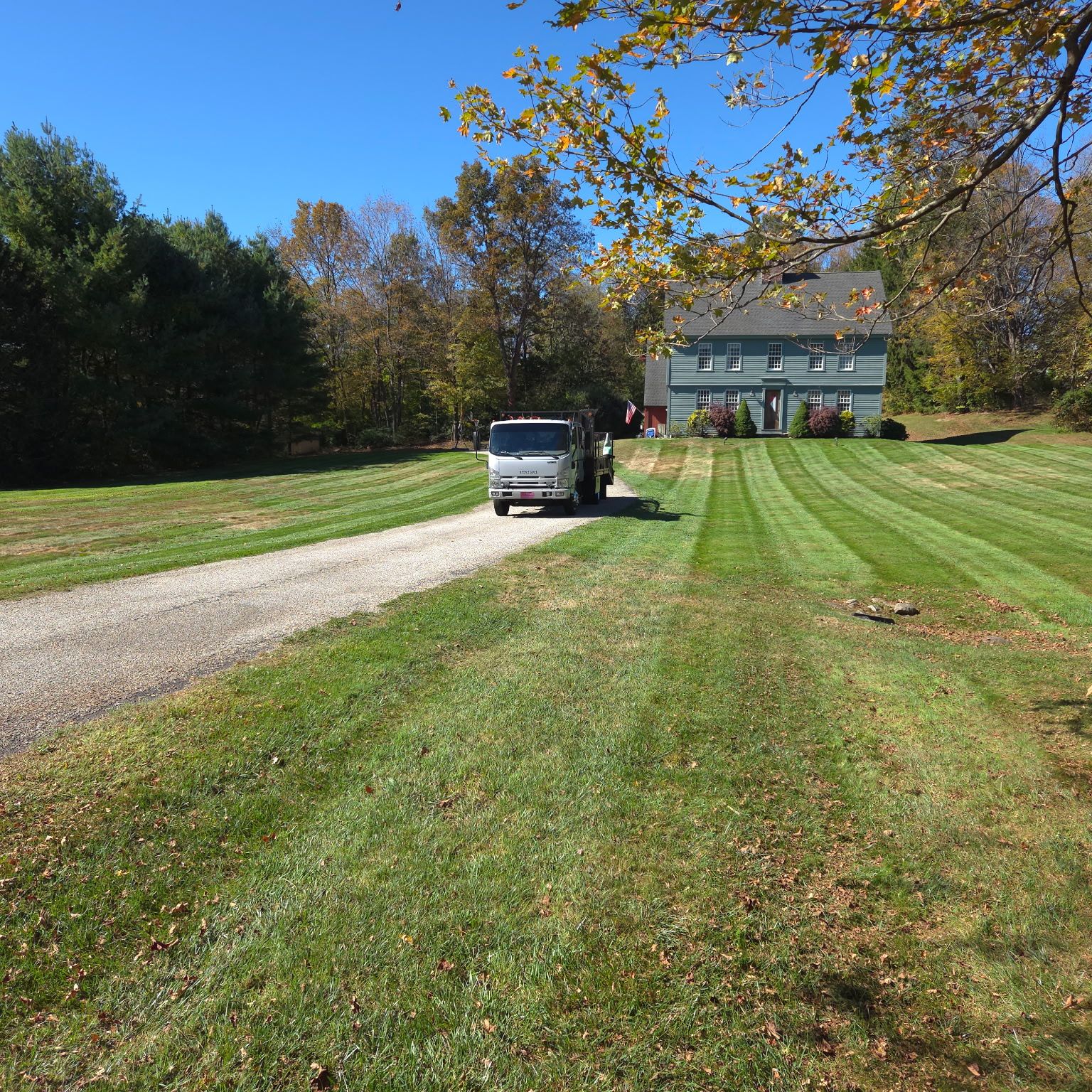 lawn mower repair watertown ct with service truck parked on a driveway beside a striped lawn