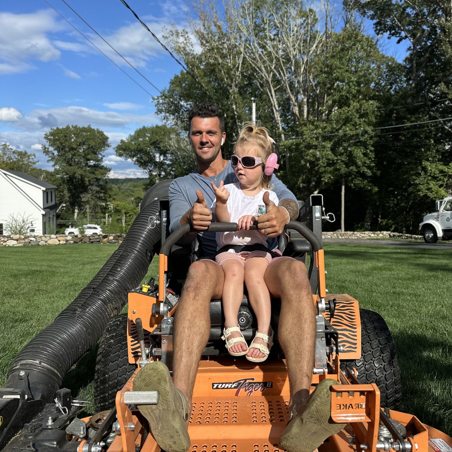 lawn mower repair watertown image showing a commercial mower with a man and child seated outdoors
