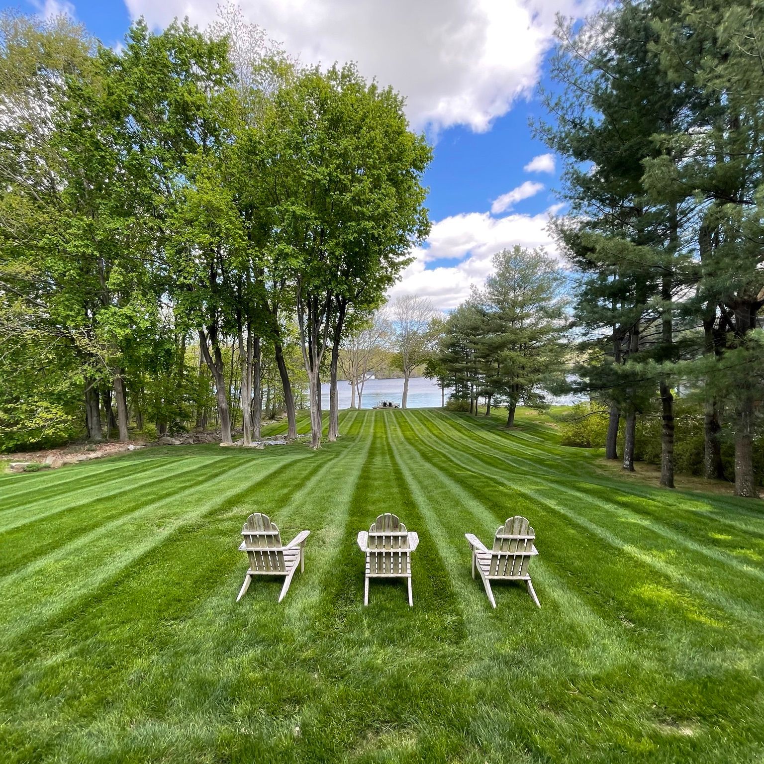 lawn mowing Watertown CT on a lakeside lawn with Adirondack chairs facing the water